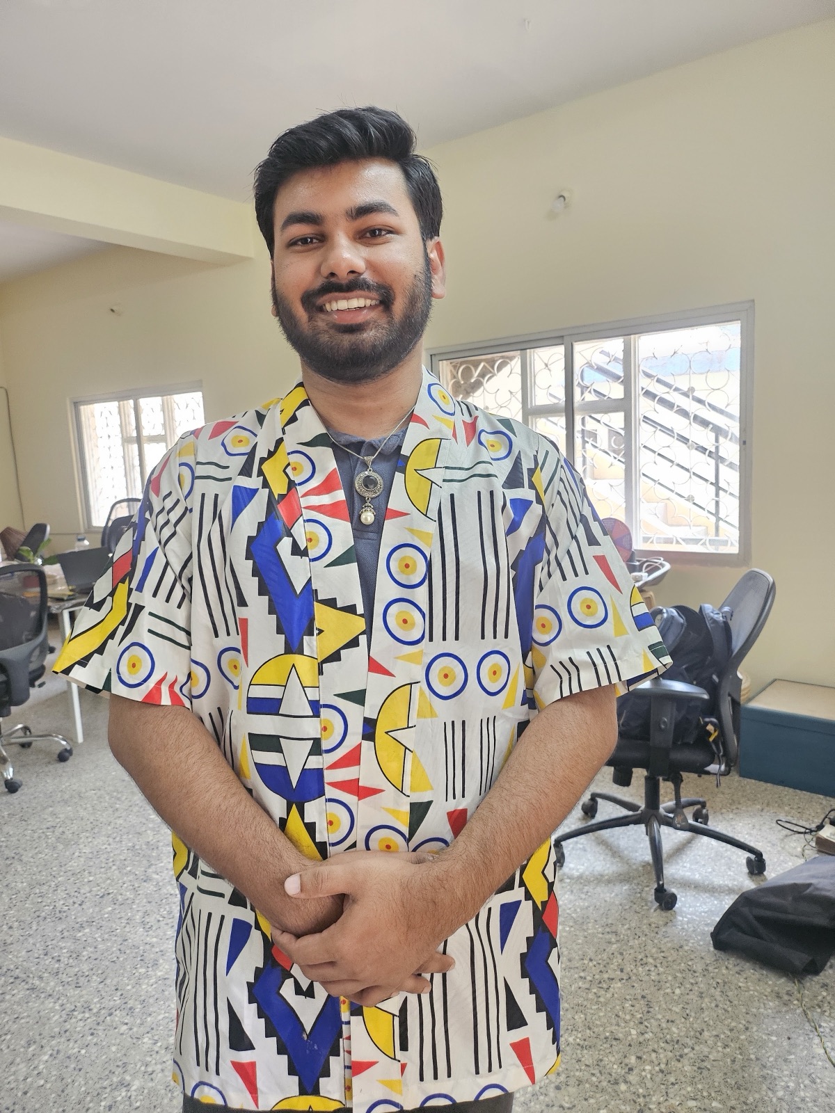 A man grinning in a geometric shirt