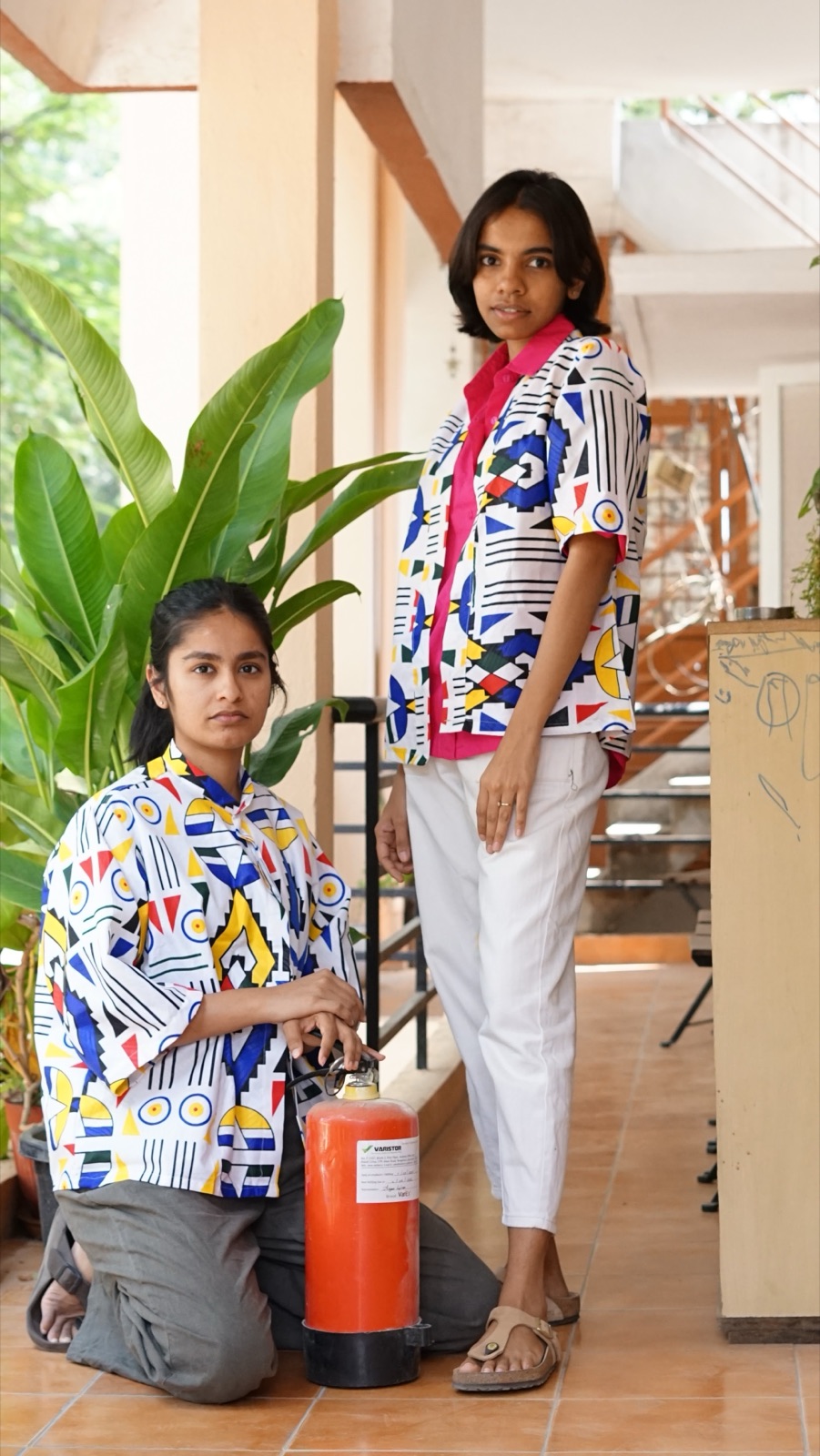 Two models in geometric shirts, one kneeling