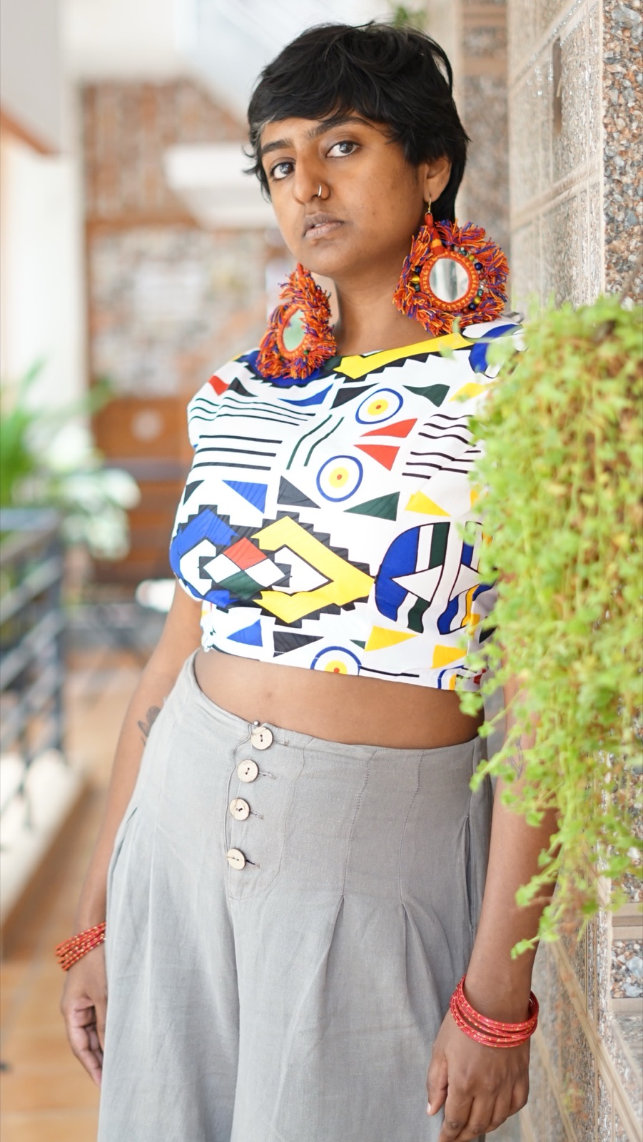 A crop top in the geometric print with grey wide-leg trousers