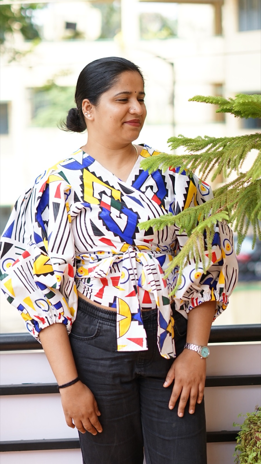 A wrap top in a blue, yellow and white Ndebele-style geometric print, tied at the waist