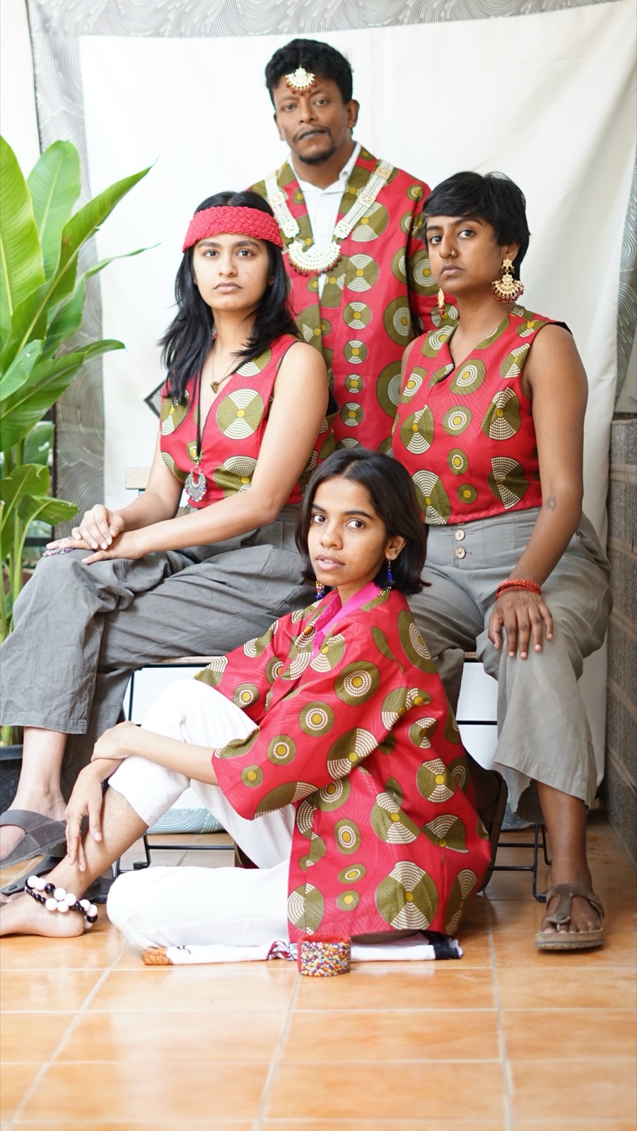 Four people posed together in pink wax-print pieces