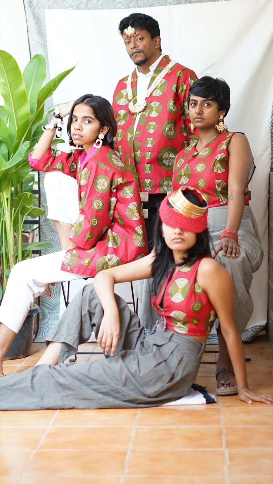 Five people in pink wax-print pieces, one lying across the floor with a red blindfold