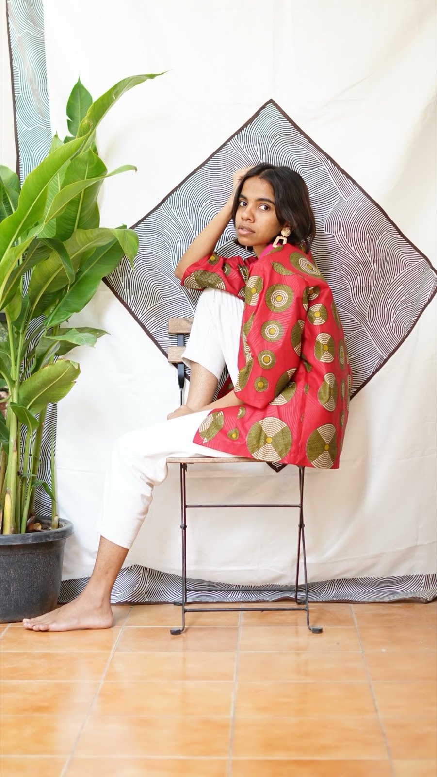 A short kimono jacket in a pink wax print, worn open over white trousers